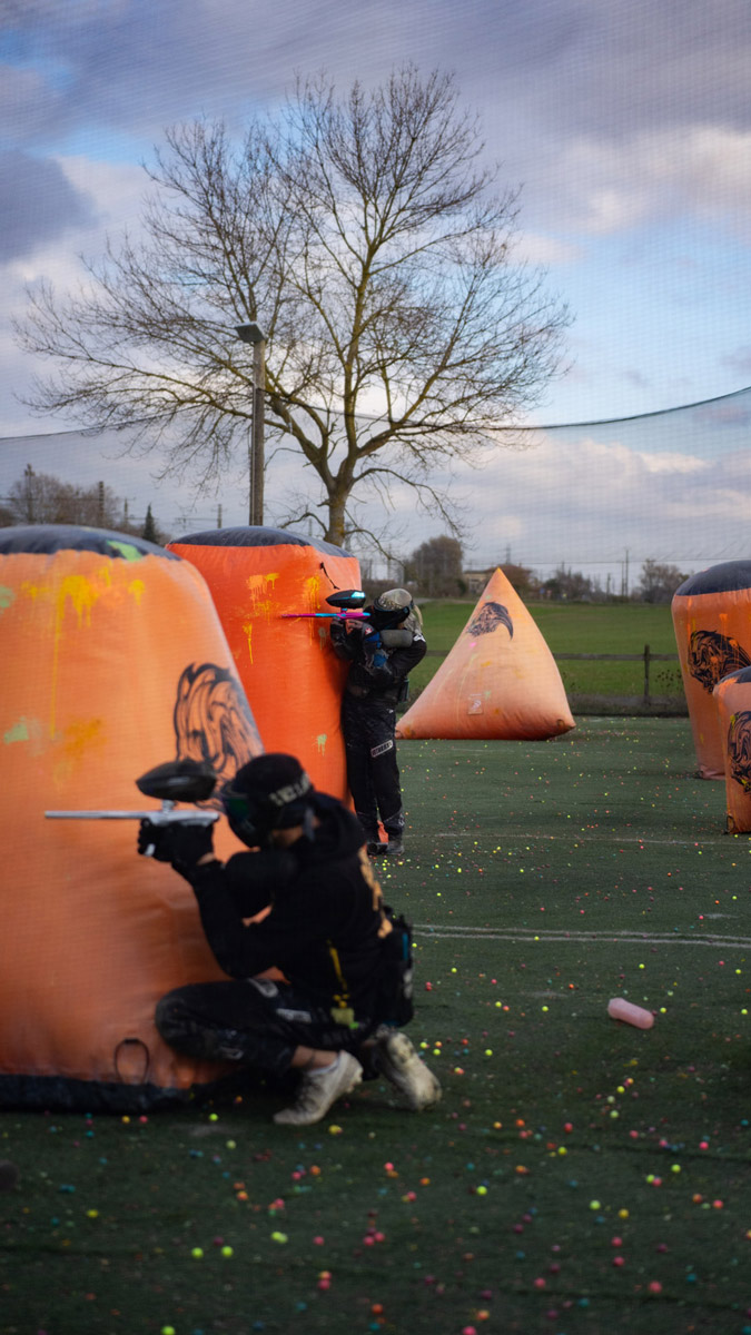Photo de joueurs de paintball en action derrière des obstacles gonflables, en pleine partie stratégique sur un terrain extérieur.
